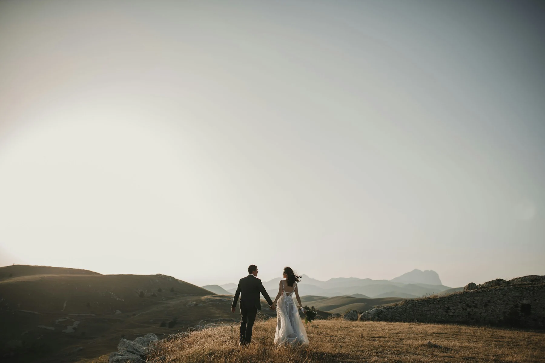 A real bride and groom walking together, photographed from behind